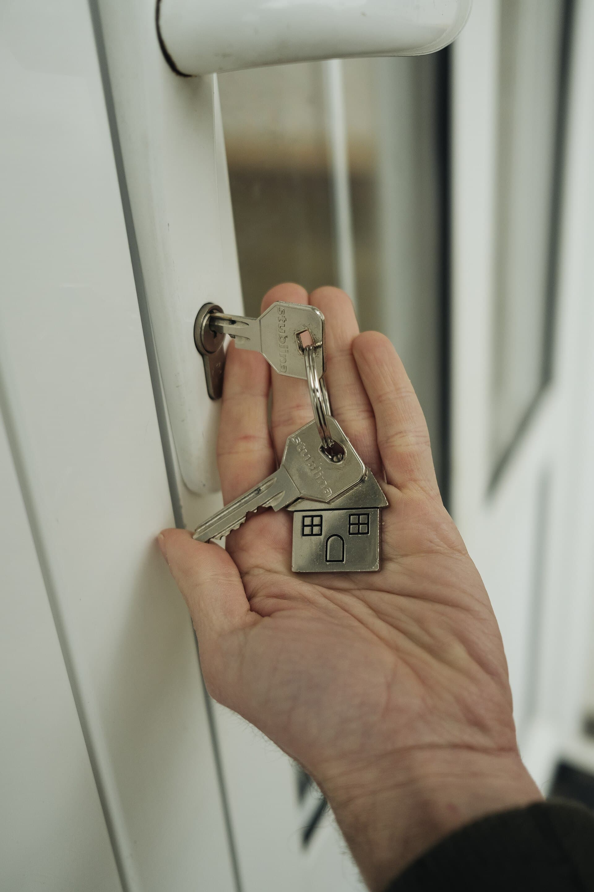 A hand holding house keys near a door lock